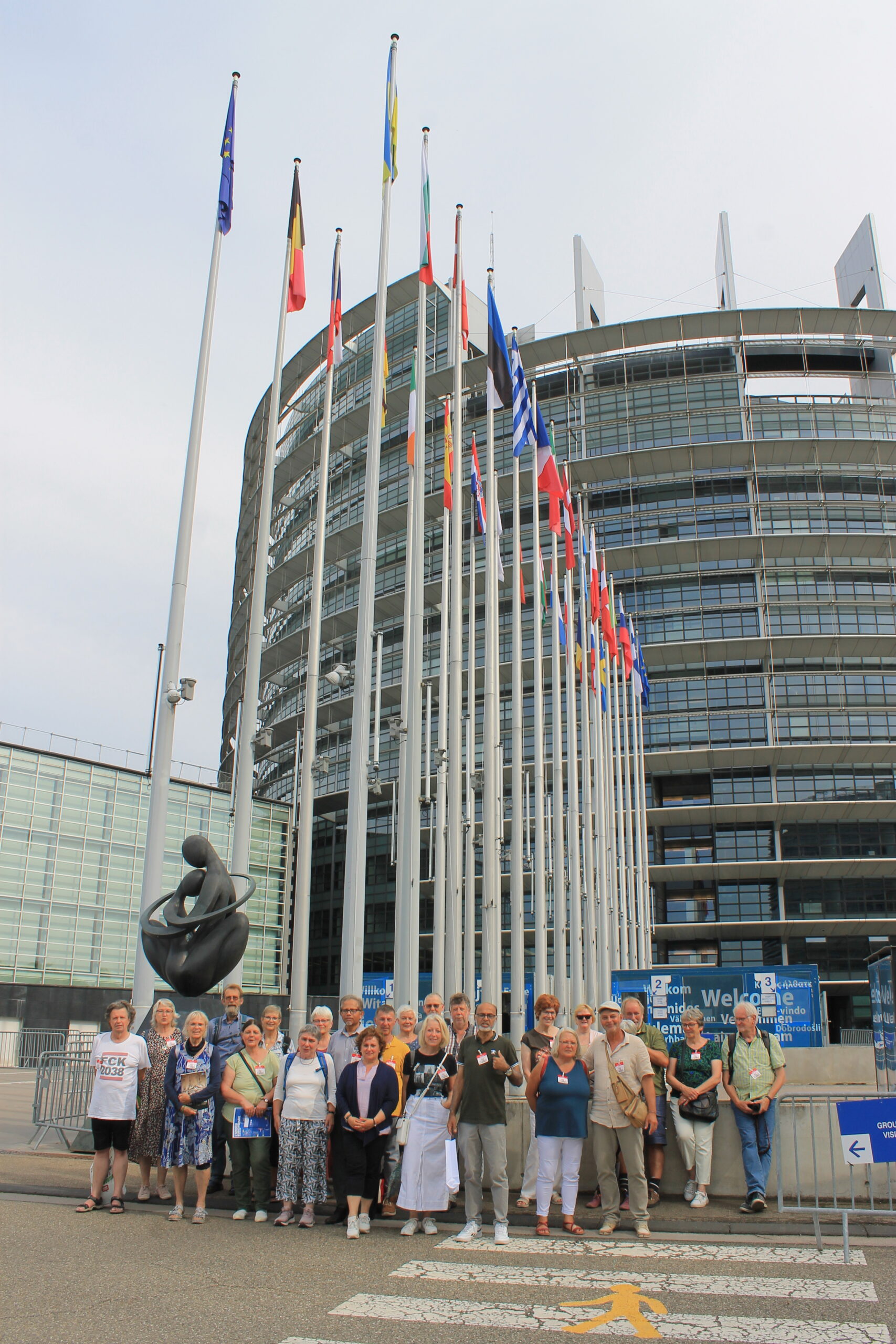 Personengruppe vor dem Gebäude des Europäischen Parlaments, Fahnen im Hintergrund