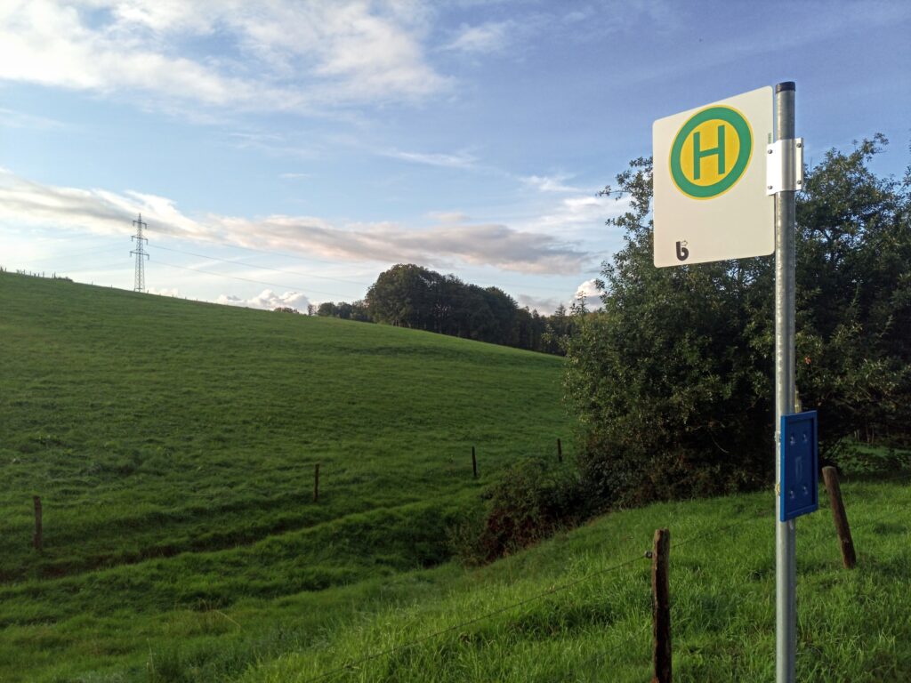 Ein Schild Bürgerbus Haltestelle vor grünen Wiesen und blauem Himmel