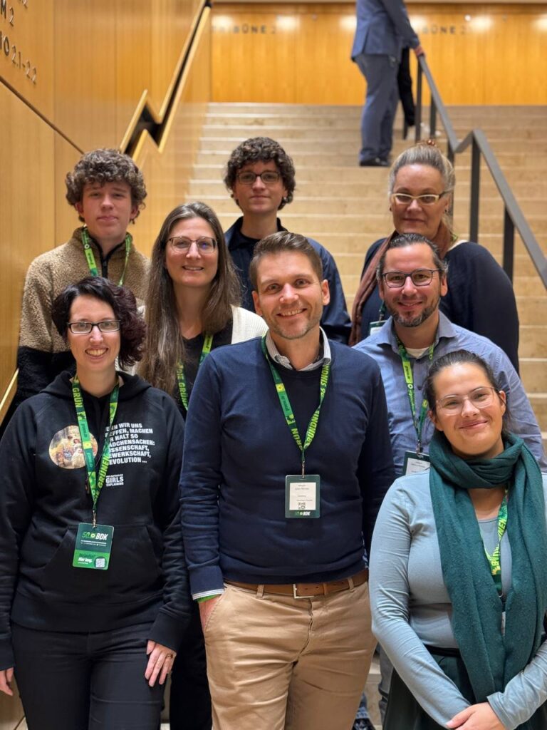 8 Personen stehen lächelnd auf einer Treppe